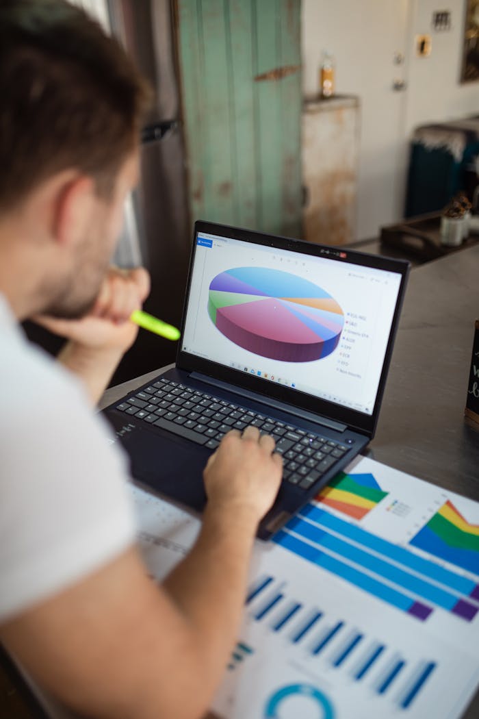 why-choose-us Focused man analyzing colorful bar and pie charts on laptop in modern office.